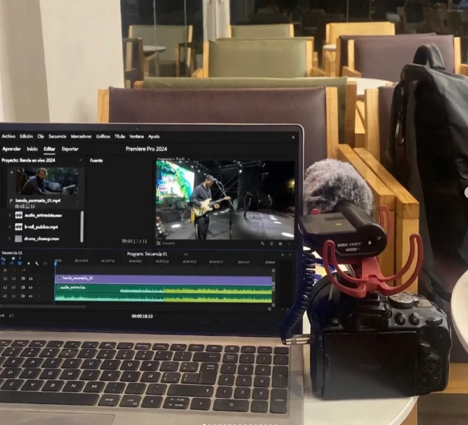 Laptop con Premiere Pro editando un video de una banda en vivo, junto a una cámara con micrófono Rode