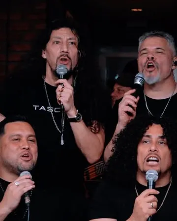 Los Nombradores del Alba cantando juntos con micrófonos durante la Gala de Folklore