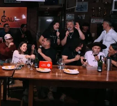 Músicos cantando alrededor de una mesa larga con vino durante la Gala de Folklore
